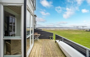 Een houten terras met uitzicht op strand en duinen.