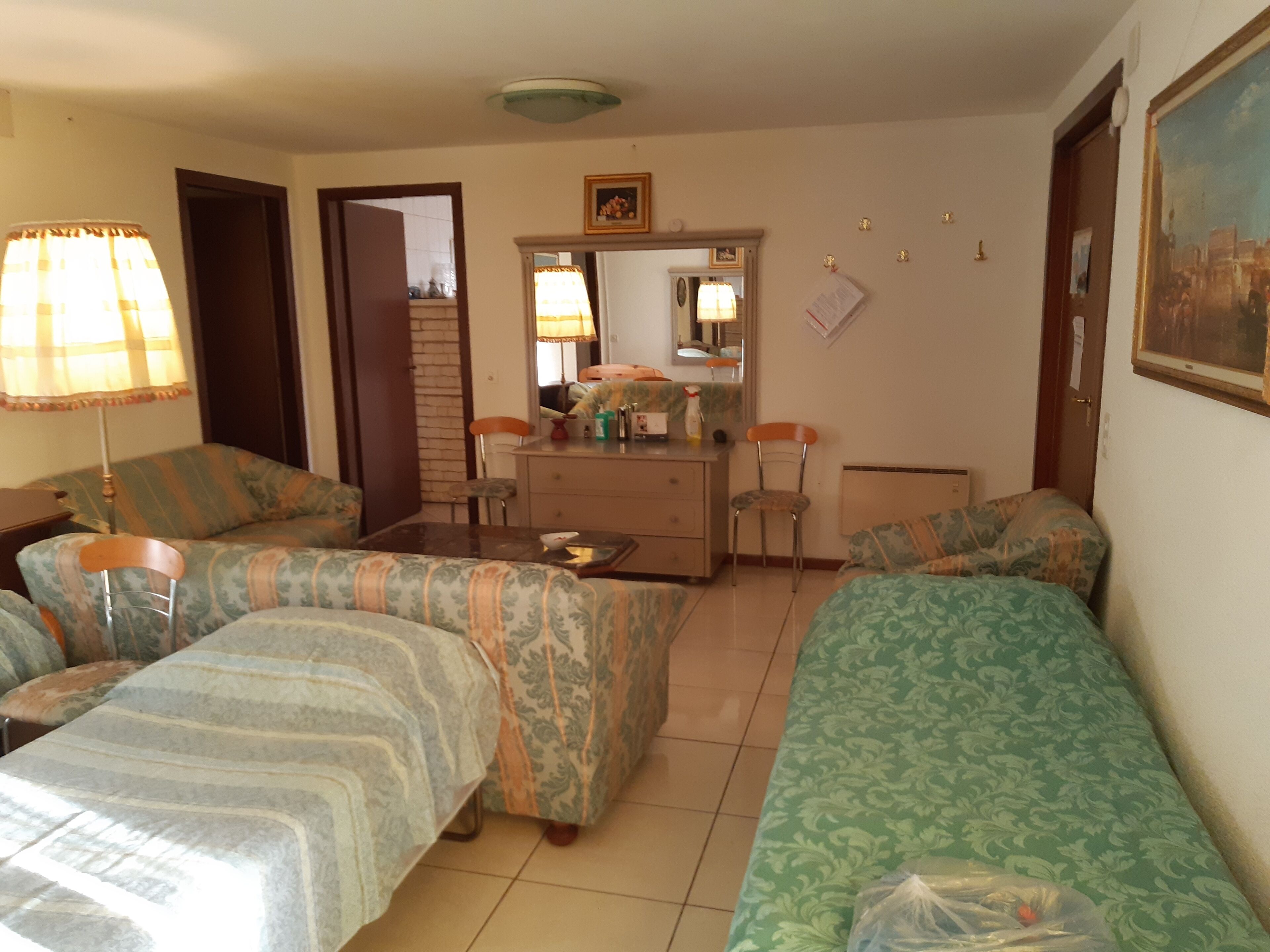A hotel room with two beds, a dresser, a mirror, and a painting on the wall.