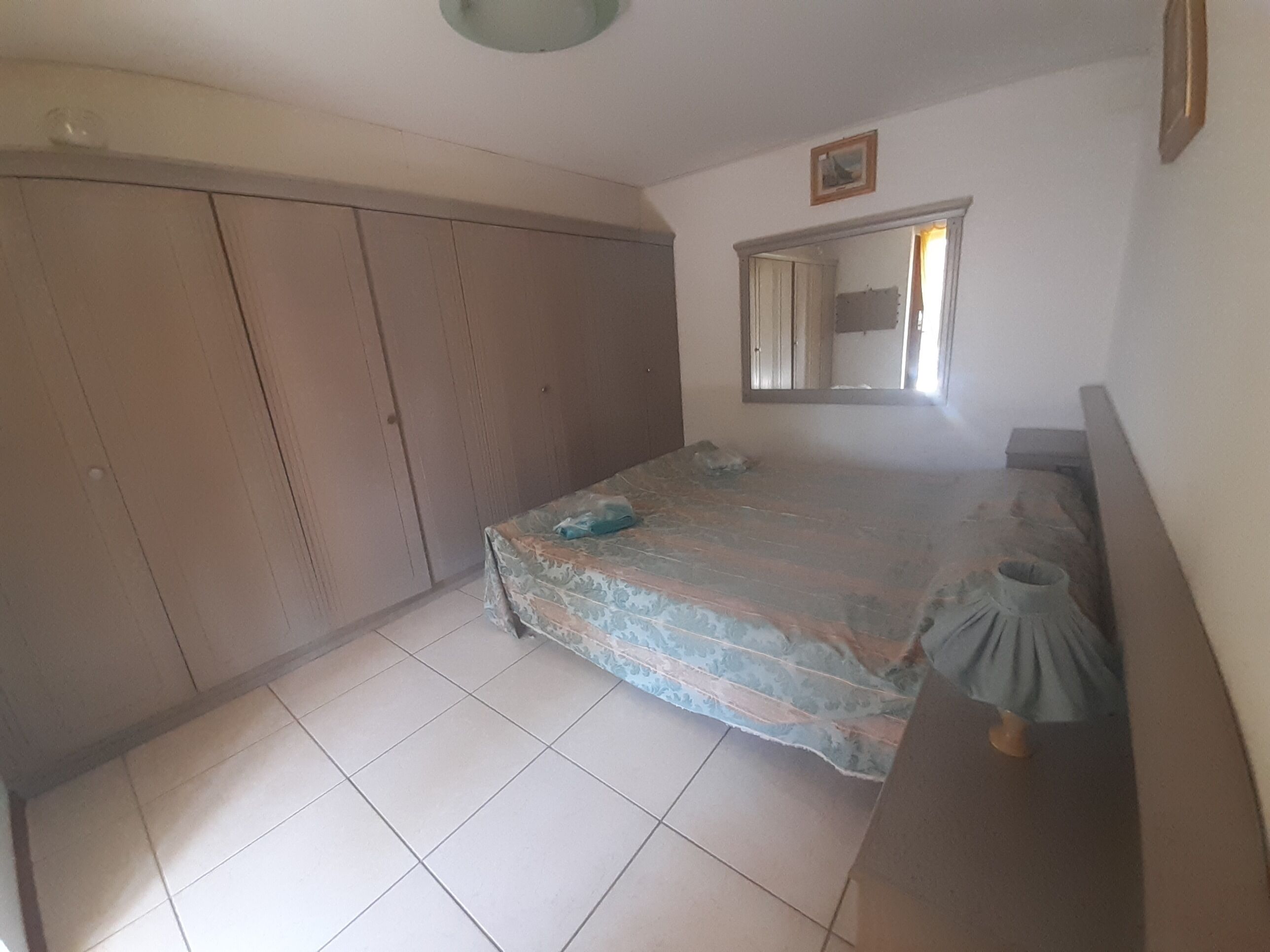 Un dormitorio con cama, armario, espejo y cómoda.