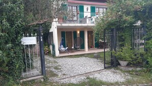 Een huis met balkon, een bord dat het een vakantiehuis aanduidt, en een grindpad.