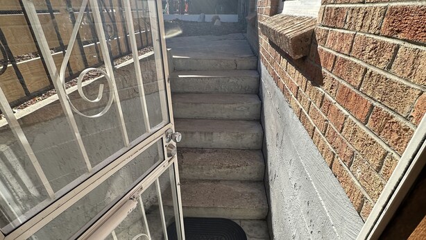 Eine enge Treppe mit einem Metallgitter und einer Backsteinmauer.