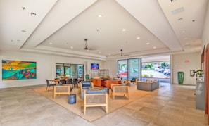 A spacious lobby with a high ceiling, a large painting, a reception desk, seating area, and a view of the parking lot.