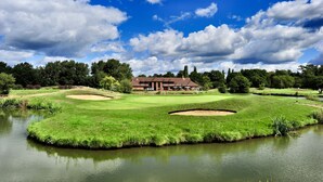 En golfbana med ett klubbhus, dammar och en klar himmel.
