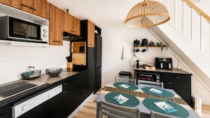 Una cocina compacta equipada con lavavajillas, microondas y un pequeño comedor con mesa y sillas.