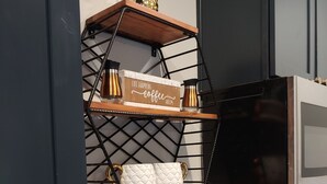 Una cocina con un lavamanos de acero inoxidable, una estufa moderna y un estante decorativo con un cartel que dice 'Life Happens Coffee Helps'.