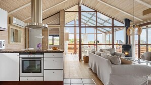 A modern kitchen with a large island, built-in oven, and a dining area with a sofa and fireplace. - Amazing home in Sjølund with WiFi (Sjølund)