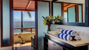 Un baño con un espejo grande, un lavabo y vistas al mar.