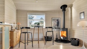 A cozy room with a wooden interior, a large window, a black stove, and a poster on the wall. - Lovely home in Hals with kitchen (Hals)