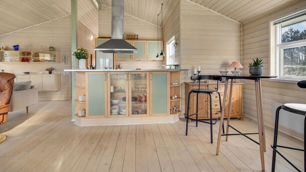 A spacious kitchen with wooden cabinets, a central island, and a large window providing a view of the outdoors. - Lovely home in Hals with kitchen (Hals)