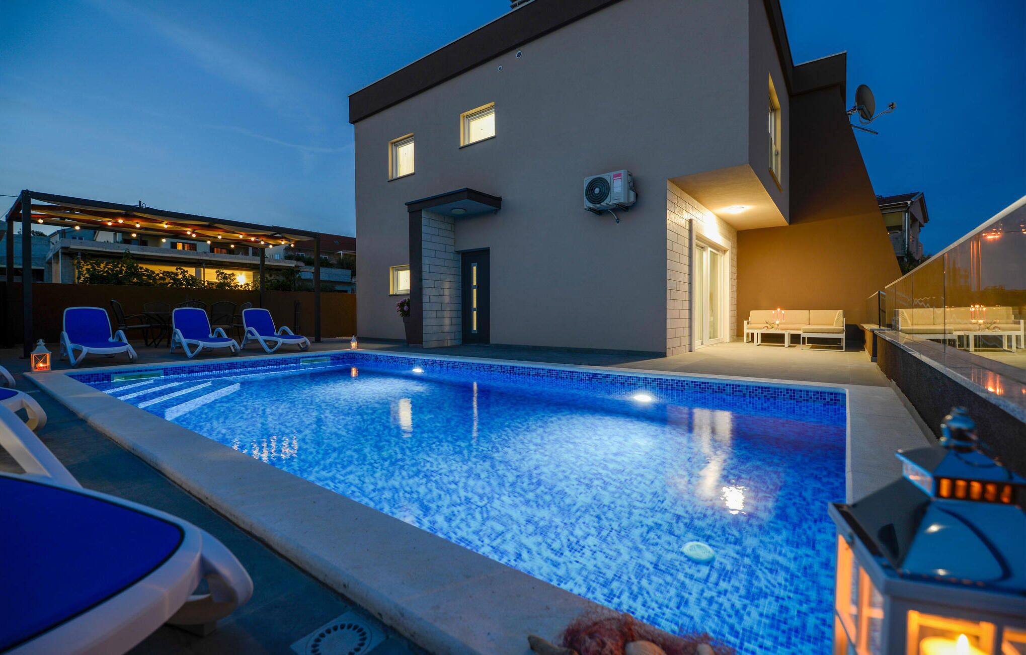 A modern hotel with a swimming pool, lounge chairs, and a well-lit outdoor seating area.