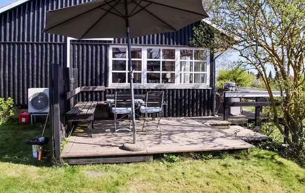 An outdoor patio with a table and chairs, a large umbrella, and a window overlooking a garden. - Gorgeous home in Vordingborg with WiFi (Vordingborg)