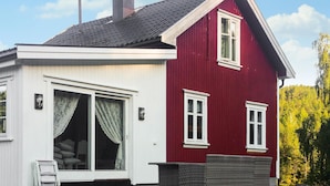 Una casa de color rojo y blanco con chimenea, puerta corrediza de vidrio y un pequeño porche.