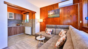 A cozy living room with a sofa and a small table, a kitchen with wooden cabinets, and a radiator. - Awesome home in Gudovac (Gudovac)
