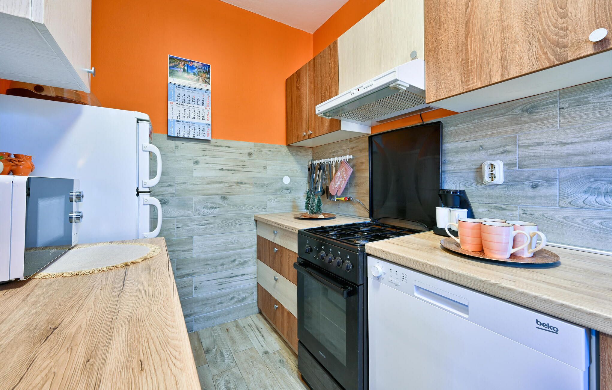 A modern kitchen with a wooden countertop, a stove, a dishwasher, and a refrigerator.
