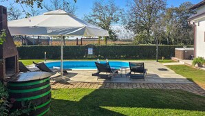 A backyard with a swimming pool, lounge chairs, a barbecue grill, and a covered patio area. - Awesome home in Gudovac (Gudovac)