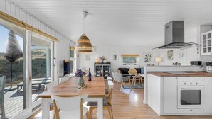 Una cocina amplia con una isla de madera, armarios blancos y un gran ventanal con vistas a una terraza.