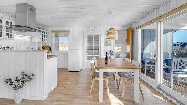 Una cocina moderna con armarios blancos, una mesa de comedor de madera y un ventanal con vistas panorámicas.