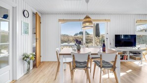 Una sala de estar moderna con comedor, ventanas amplias y televisor.
