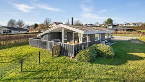 Et moderne, etetages hus med en overdækket terrasse og en indhegnet have.