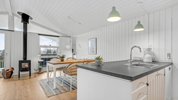 Et moderne køkken med en central ø, indbygget komfur og hængende lamper.