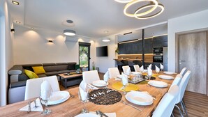 Comedor moderno con una mesa de madera dispuesta para seis personas, rodeada de sillas blancas.