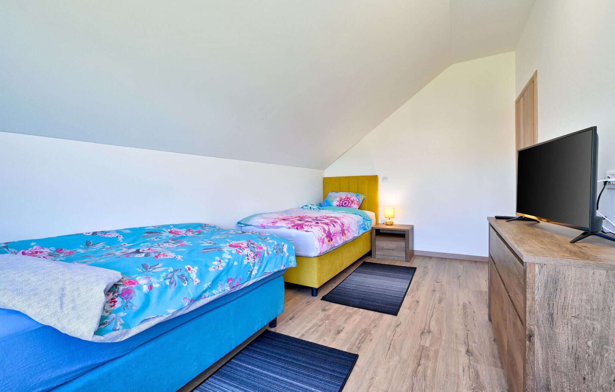 Ein Schlafzimmer mit zwei Betten, einem Fernseher und einem Schreibtisch.