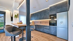 Una cocina moderna con encimera de madera, electrodomésticos de acero inoxidable y taburetes de bar.