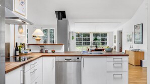 A modern kitchen with white cabinetry, a wooden countertop, a Bosch dishwasher, and a large window providing a view of the outdoors. - Cozy home in Grenaa with WiFi (Grenaa)