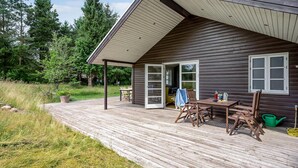 A wooden cabin with a covered deck, a dining table, and chairs. - Cozy home in Grenaa with WiFi (Grenaa)
