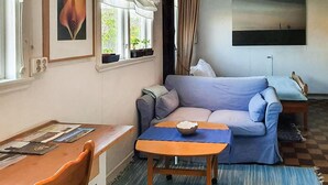 En hyggelig stue med en sofa, et lille bord og et vindue med gardiner.