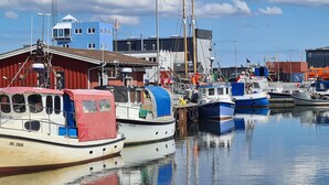 A marina with several boats docked, a red building, and a blue building in the background. - 3 bedroom nice home in Hvide Sande (Hvide Sande)