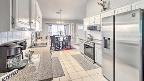 A modern kitchen with stainless steel appliances, a coffee maker, and a dining area with a table and chairs. - LUXURY GETAWAY, 4 BR, 2.5 BATH, NEAR FT. STEWART (Hinesville)