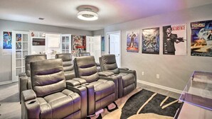 A home theater with three leather reclining chairs, a carpeted floor, and movie posters on the wall. - LUXURY GETAWAY, 4 BR, 2.5 BATH, NEAR FT. STEWART (Hinesville)