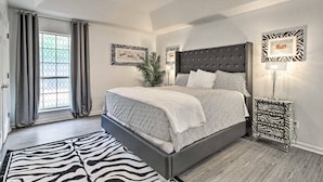 A bedroom with a large bed, a zebra-patterned rug, and a ceiling fan. - LUXURY GETAWAY, 4 BR, 2.5 BATH, NEAR FT. STEWART (Hinesville)
