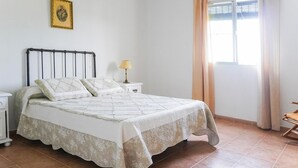 A bedroom with a bed, nightstand, lamp, and a window with curtains.