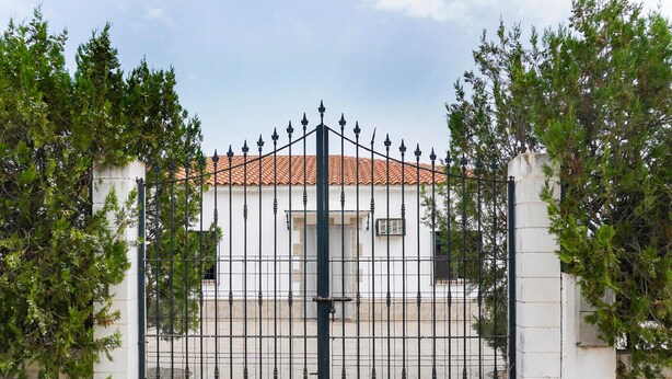 A gated property with a white building featuring a tiled roof.