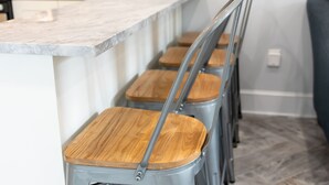 A kitchen with a marble countertop, wooden stools, and a stainless steel oven. - TROPICAL PROPERTIES VACATION RENTAL - KEY WEST (Key West)