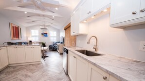 A modern kitchen with white cabinetry, a marble countertop, and a built-in dishwasher. - TROPICAL PROPERTIES VACATION RENTAL - KEY WEST (Key West)