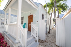 A white house with a porch, a wooden door, and a mailbox.