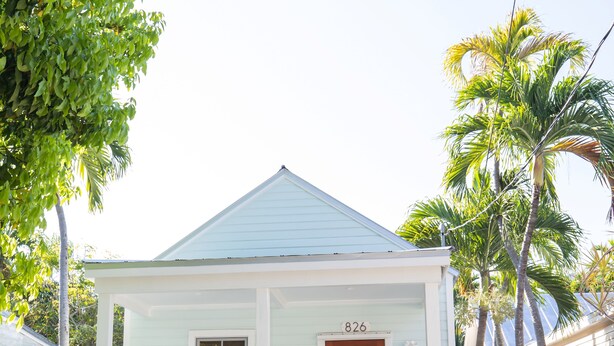 A light blue house with a white porch and a number '826' sign. - TROPICAL PROPERTIES VACATION RENTAL - KEY WEST (Key West)