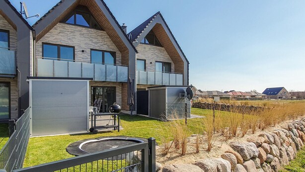 A modern two-story house with a stone facade, large windows, and a visible outdoor grill area. - Awesome home in Büsum with sauna (Büsum)