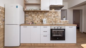 A compact kitchen with a refrigerator, oven, and a wooden countertop. - Lovely apartment in Cres with WiFi (Cres)