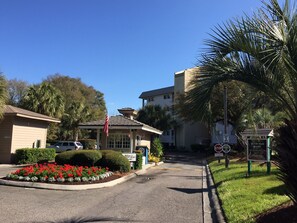 Katunäkymä, jossa näkyy rakennus, jonka kyltissä lukee ”Hilton Head Resort”, stop-merkki ja nopeusrajoitusmerkki, jossa lukee 10 mph (noin 16 km/h).