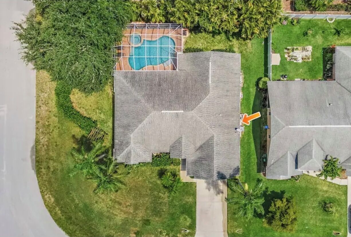 An aerial view of a residential property with a swimming pool, a large house, and a smaller structure.