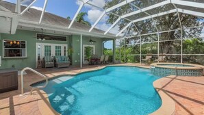 Ein Swimmingpool mit überdachtem Patio, einem Deckenventilator und Blick auf die umliegenden Bäume.