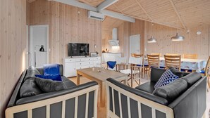 A modern interior with a wooden ceiling, a dining area with a table and chairs, a sofa, a TV, and a kitchen area. - 4 bedroom stunning home in Ribe (Ribe)