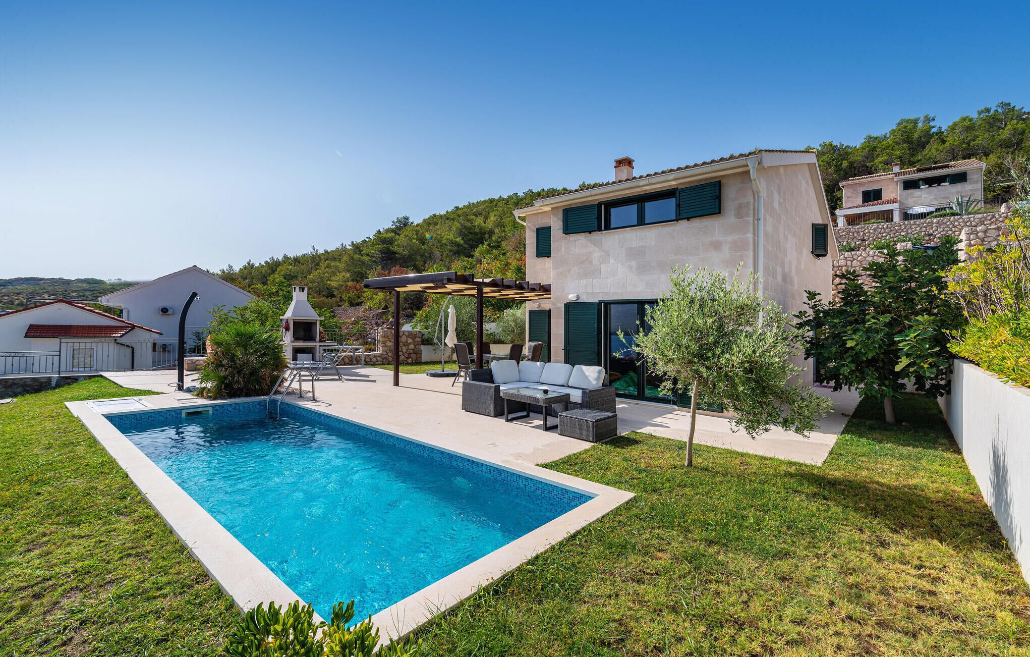 Une maison moderne dotée d’une piscine, d’un espace salon extérieur et d’un mur en pierre.