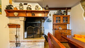 Ein gemütliches Wohnzimmer mit Kamin aus Stein, Holzregalen und einer Holzkabine mit Glastüren.