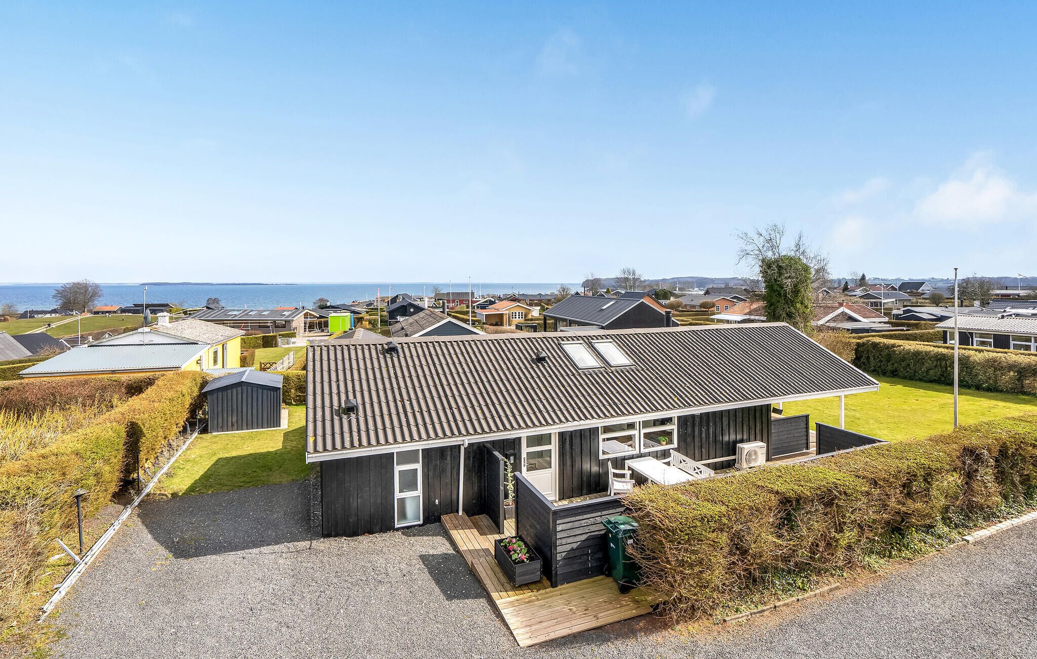 A coastal house with a tiled roof, a small deck, and a view of the sea.