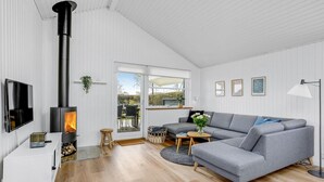 Una sala de estar moderna con chimenea, un sofá gris, un televisor y piso de madera.
